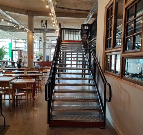 Escalier droit avec accès sur palier installé au sein d’un restaurant
			