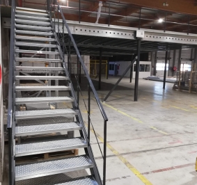 Escalier industriel métallique installé dans entrepôt pour permettre l’accès à une plateforme
			