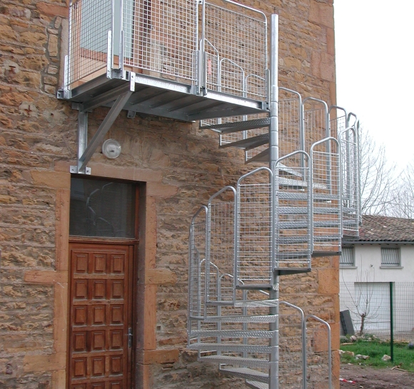 Escalier hélicoïdal en acier permettant un accès extérieur au 1er étage d’un bâtiment
					                    