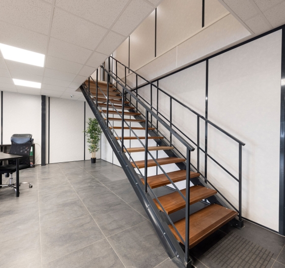 Escalier métallique avec des marches en bois installé au sein de locaux professionnels pour permettre l’accès à l’étage supérieur
		                    